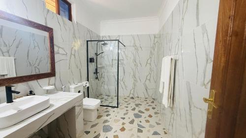 a bathroom with a shower and a toilet and a sink at Moya Beach Hotel in Marumbi