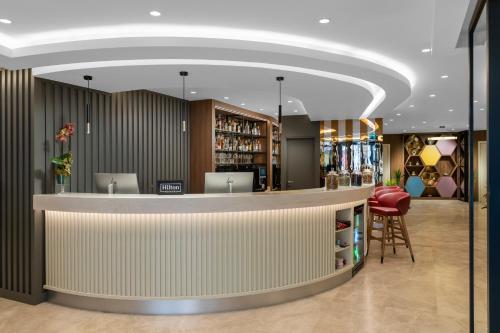 Un vestíbulo con un bar con un taburete rojo. en Hampton By Hilton Istanbul Sisli, en Estambul