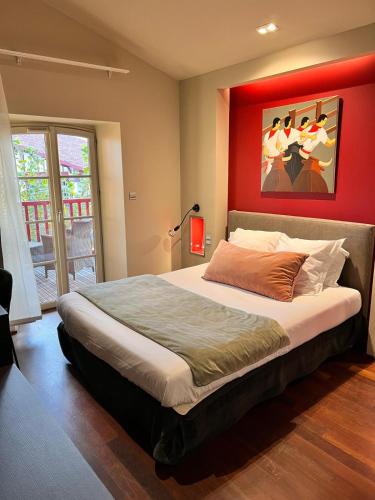 a bedroom with a large bed with a red wall at Hotel du Fronton in Bidart