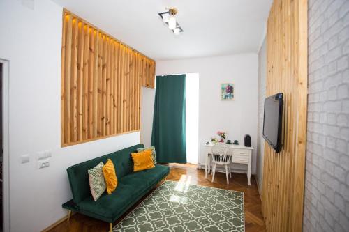 Una sala de estar con un sofá verde y un televisor. en Joseph Hayn Apartments, en Sighişoara