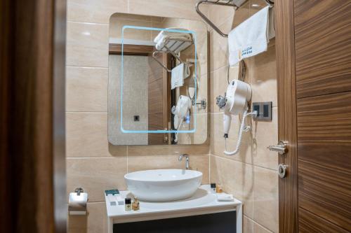 a bathroom with a sink and a mirror at Bloom Hotel - فندق بلوم in Baghdad