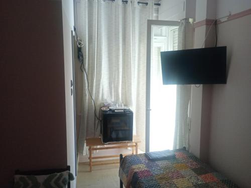 a room with a bed and a tv and a window at The cabin in Loutraki