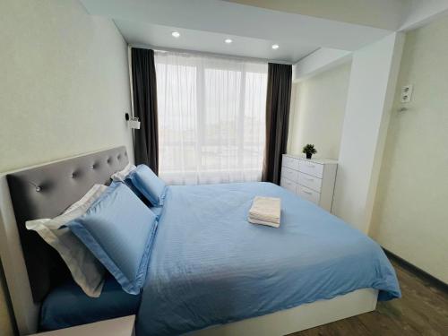 a bedroom with a blue bed with a window at Malldova Chișinău centru in Chişinău