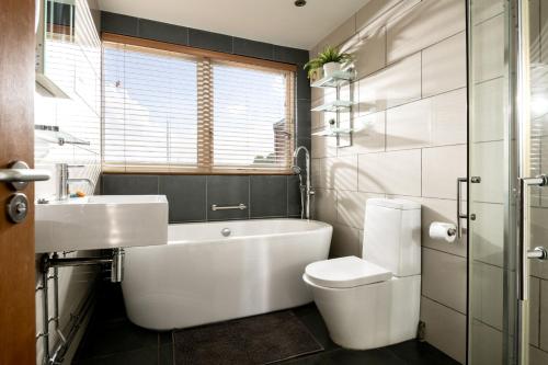 a bathroom with a tub and a toilet and a sink at The Garden House in Waterden