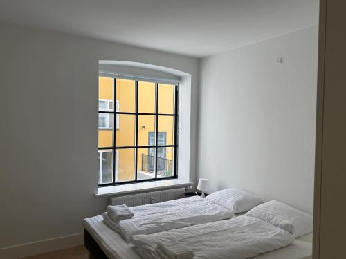 two beds in a room with a large window at Modern & Stylish Serviced Apartment in Odense in Odense