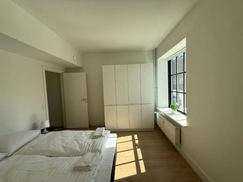 オーデンセにあるCentral Odense Lovely Apartmentのベッドと窓のある白い寝室