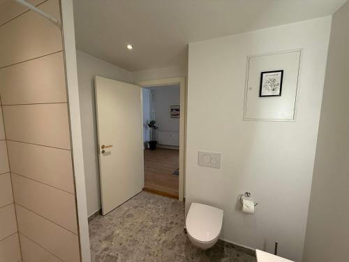 a white bathroom with a toilet and a door at Luxurious Odense Residence in Odense