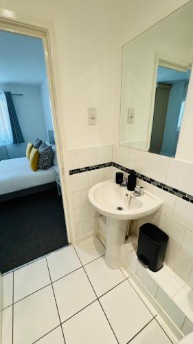 a bathroom with a sink and a mirror and a bed at Spacious Ground Floor 2-Bed Flat - Patio, Parking - By Habitats in Southampton