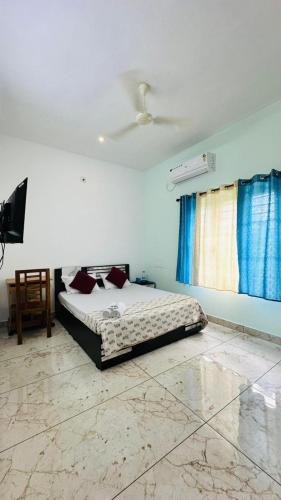 a bedroom with a bed and a tv in it at Rams Guest House Meadows Walk to Varkala Papnasam Beach - Groups & Couple friendly in Varkala
