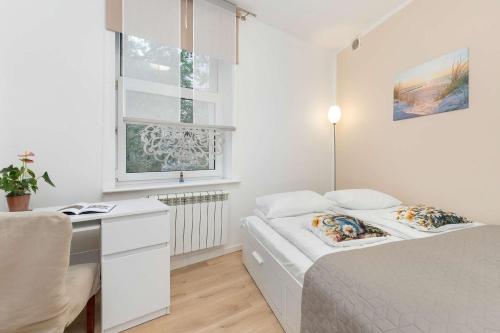 een kleine witte slaapkamer met een bed en een bureau bij Five Bedroom Apartment for 12 in Gdańsk Center with Desk and Balcony by Noclegi Renters in Suchanino