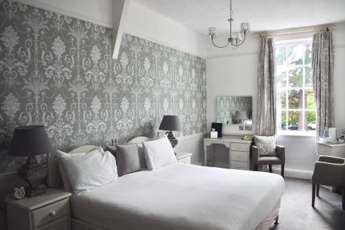 a bedroom with a large white bed and a desk at Hunters Moon Hotel in Sidmouth