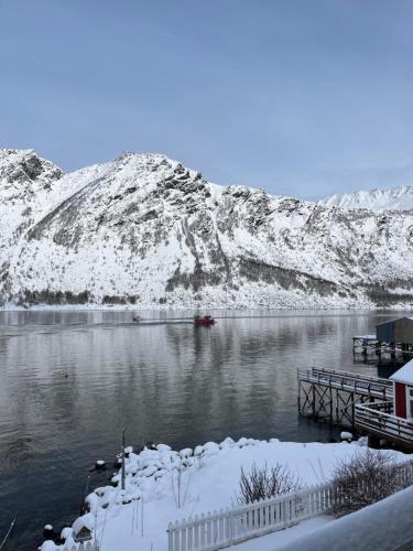 a body of water with a dock and snow covered mountains at Fantastic house with seafront property in Gryllefjord in Gryllefjord