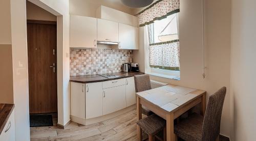 a kitchen with white cabinets and a table and a window at Ecoappart-Haz in Mosonmagyaróvár