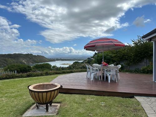een houten terras met een tafel en een parasol bij Traka Cottages in Sedgefield