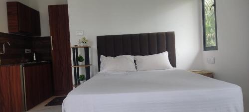 a bedroom with a large white bed with a black headboard at Flumen Resort in Ernakulam