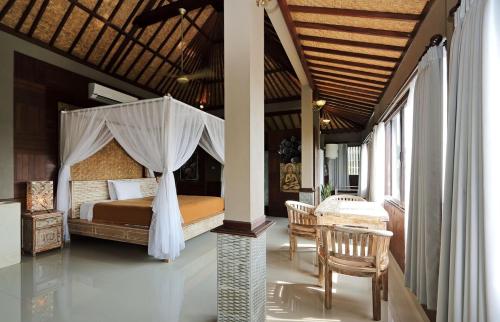 a bedroom with a canopy bed and a table and chairs at Huge Amazing Campuhan Ridge Walk view room in Ubud