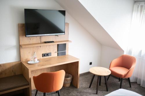 a living room with a tv and two chairs at Landgasthof Kinzigstrand in Biberach bei Offenburg