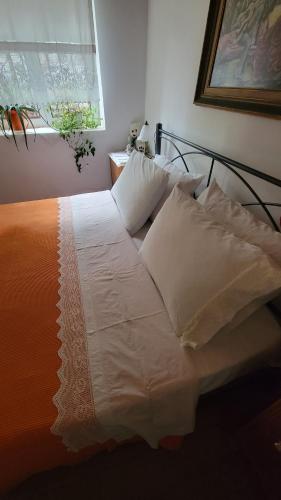a bed with white sheets and pillows in a bedroom at Xhumba Guesthouse in Dhuvjan