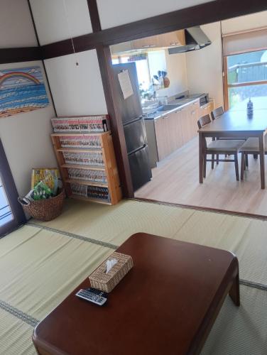 a living room with a table and a kitchen at MATAHARI Guesthouse in Miyazaki