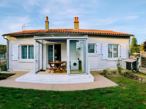 une petite maison blanche avec une table devant dans l'établissement Cottage Chaleureux Proche Ocean, à Salles-sur-Mer