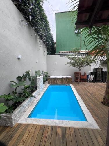 a swimming pool in a backyard with a wooden deck at Shankara Prime Maresias Guest House in Maresias