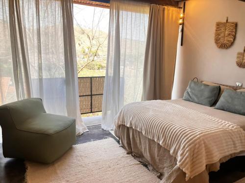 a bedroom with a bed and a chair and a window at Fraga da Mantiqueira in São Bento do Sapucaí
