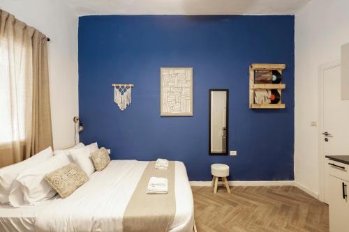 a bedroom with a blue wall and a bed at Rena's House - Beach Edition in Tel Aviv