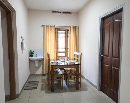 a dining room with a table and chairs and a sink at Anand homestay in Kattappana
