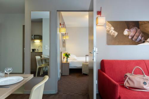 a hotel room with a red couch and a bedroom at Nehô Suites Porte de Genève - Gare Annemasse in Annemasse