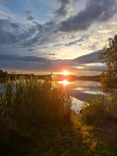 a sunset over a body of water with the sun setting at Apartma Ob jezeru in Gradišče v Slovenskih Goricah