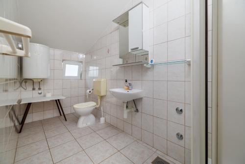 a white bathroom with a toilet and a sink at Apartments Anica J in Lopar