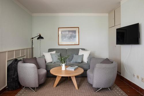 a living room with a couch and two chairs and a table at Reetdachhaus mit Nähe zur Ostsee, Außensauna, Spielplatz & großem Garten in Manhagen
