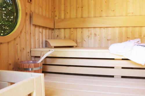 a wooden sauna with a bench and a tub at Reetdachhaus mit Nähe zur Ostsee, Außensauna, Spielplatz & großem Garten in Manhagen