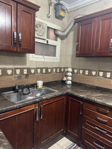 a kitchen with wooden cabinets and a sink at Atlantis Palace Pyramids View in ‘Ezbet `Abd el-Ḥamîd