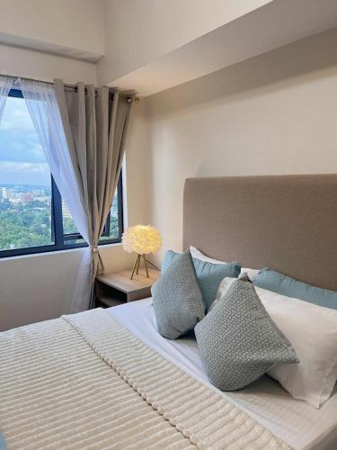 Un dormitorio con una cama con almohadas y una ventana. en ABE Place, en Cebú