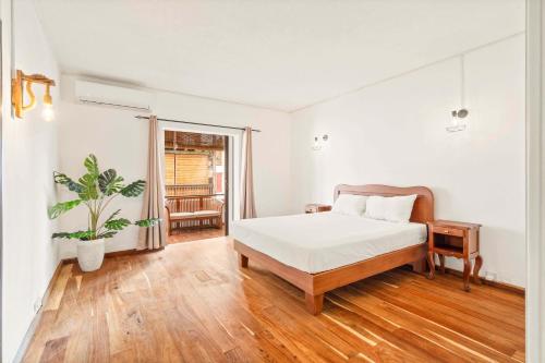 a white bedroom with a bed and a potted plant at Sunset Cove - 3Ch, Vue Lagon & Accès Plage in Grand Baie