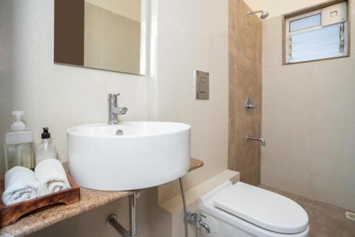 a white bathroom with a sink and a toilet at Rehano by Leo Homes - 2BHK Flat near Anjuna Beach in Anjuna