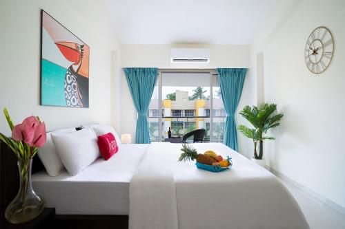a bedroom with a bed with a bowl of fruit on it at Rehano by Leo Homes - 2BHK Flat near Anjuna Beach in Anjuna