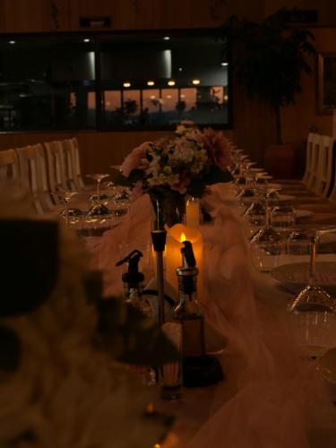 a long table with candles and flowers on it at Hani i Qerosit in Kuçovë