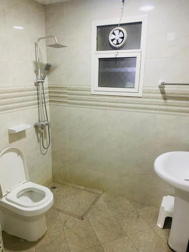 Un baño con inodoro y una ventana con reloj. en استوديو مفروش, en Ajman