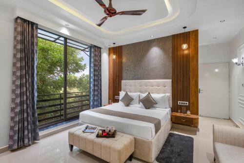 a bedroom with a large bed and a large window at Shreya Blossom Retreat 4-BHK Retreat With Private Pool, Gazebo, Garden, Bar & Scenic Aravali Views in Thūr