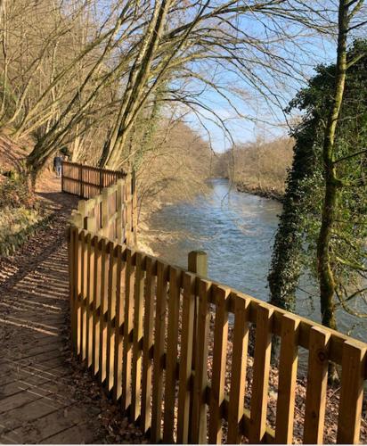 a wooden fence next to a river with a bridge at Chalet Woods in Durbuy