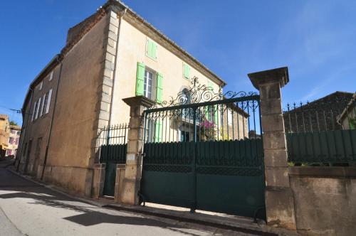 a building with a green gate on a street at Relais des Vignerons, Chambres d'hôtes in Conilhac-Corbières