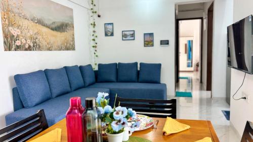 un salon avec un canapé bleu et une table dans l'établissement Casa Bloom - 2 BHK - Balewadi - Family Only, à Pune