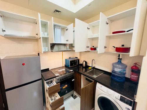 a kitchen with white cabinets and a stainless steel refrigerator at Mahenti - Lawnz · Well furnished apt with balcony in Dubai