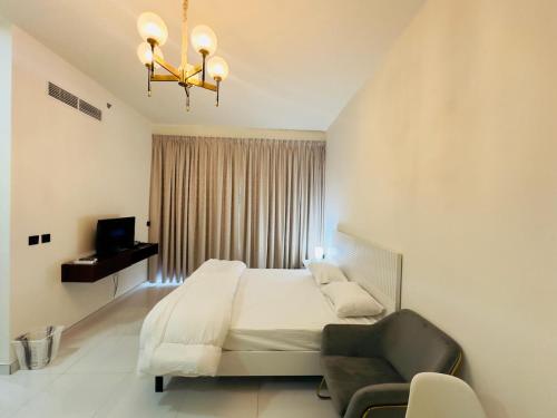 a bedroom with a bed and a chair and a chandelier at Mahenti - Lawnz · Well furnished apt with balcony in Dubai
