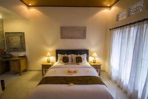 a bedroom with a bed with white sheets and a window at Umah Dajane Guest House in Ubud