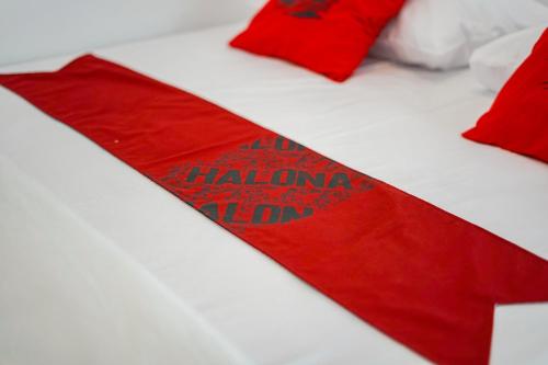 une cravate rouge sur un lit avec des oreillers rouges dans l'établissement Halona Taraman Guest House by Yurooms, à Ngemplak