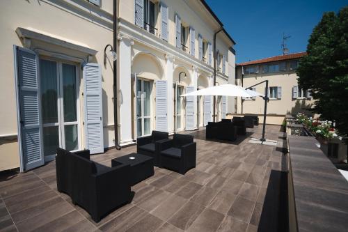a patio with chairs and an umbrella in front of a building at Rechigi Park Hotel in Modena