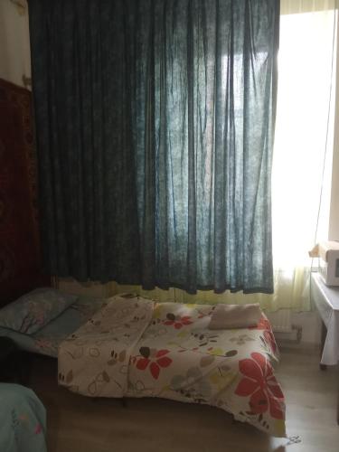 a bedroom with a bed and a window with curtains at Комната рядом с Дерибасовской in Odesa